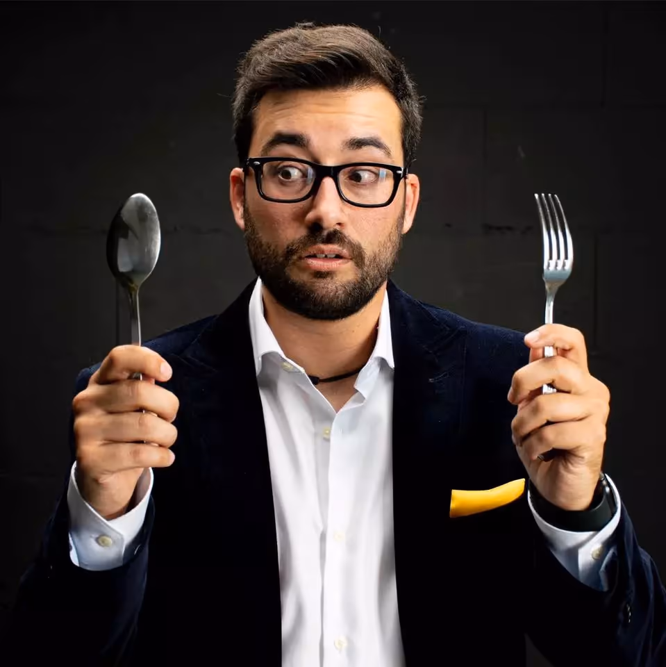 Foto artística de primer plano del mago Borjo Meyer entre una cuchara y un tenedor, jugando con la palabra entretenedor